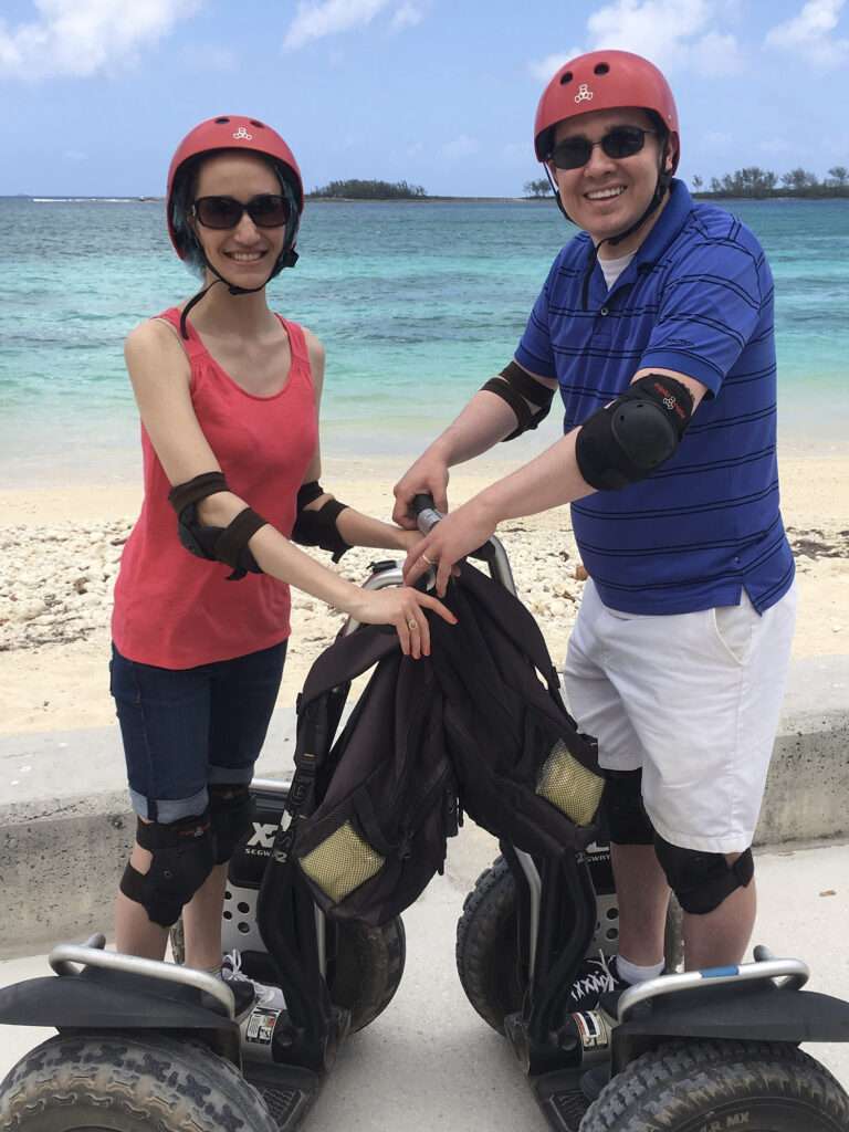Two people on Segways on a beach.