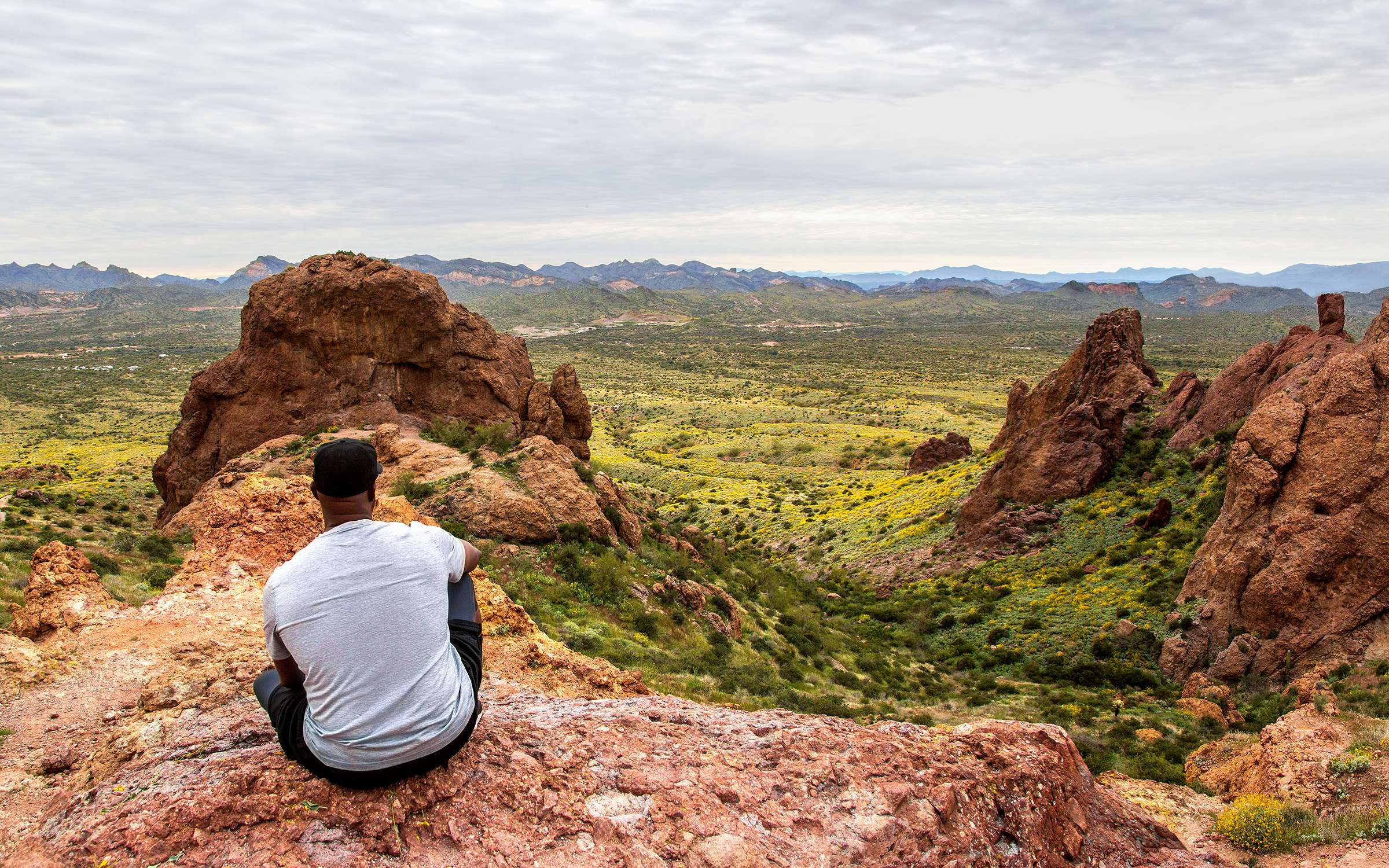 Black man sitting on a hillside and looking out at the view in Arizona