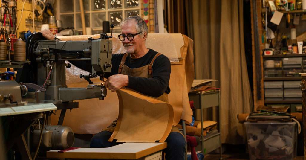 Man working leather on a leather working machine.